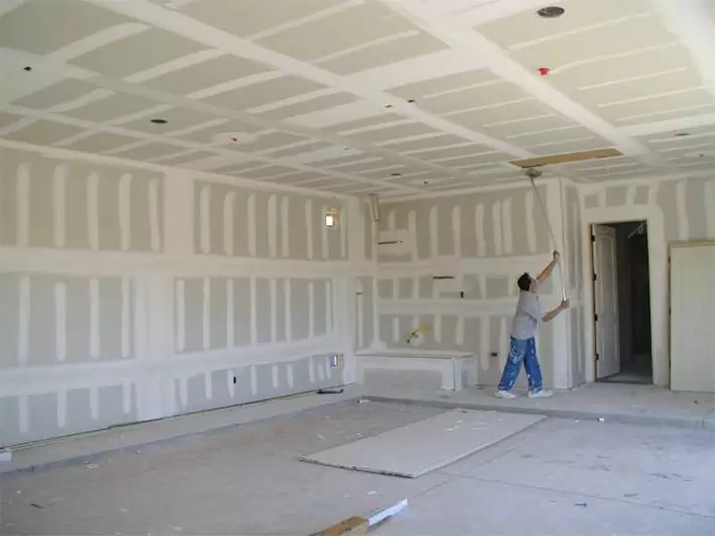 Rolling a fresh coat of paint onto a newly mudded ceiling and wall